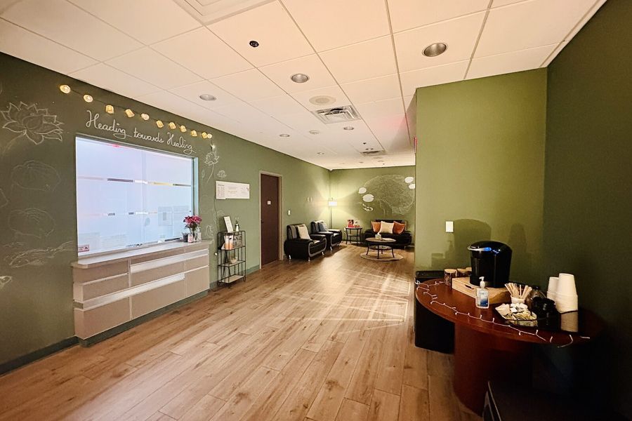 The clinic lounge at Heading Health Stone Oak — green walls, lotus chalk drawings, 'Heading towards Healing'.