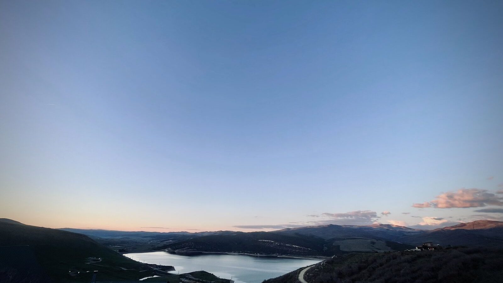 Twilight landscape over a mountain reservoir near Coalville, Utah, with a single road descending into the valley.