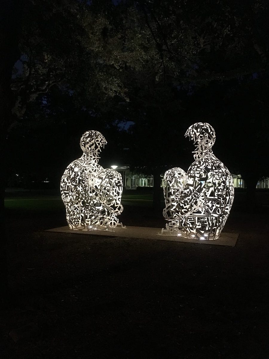 A Jaume Plensa sculpture — a large, quiet human figure sitting with closed eyes.